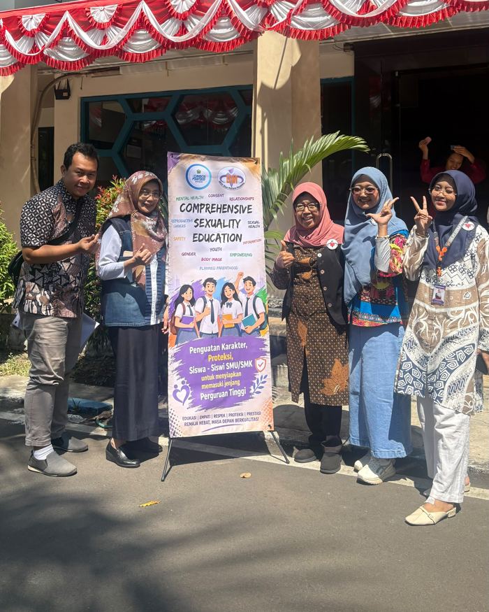 Tim WCC dan guru di samping banner Comprehensive Sexuality Education