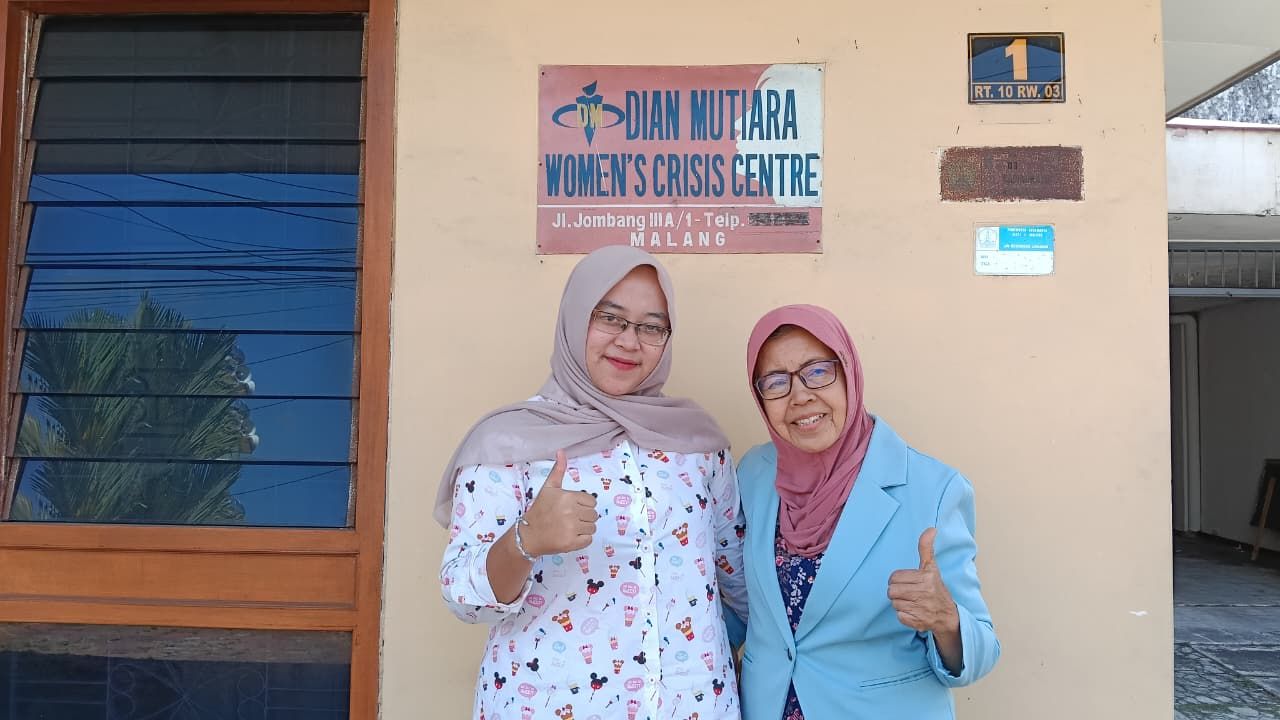 Dua pendamping WCC berdiri di depan papan nama Dian Mutiara Women's Crisis Centre, Jl. Jombang IIIA/1 Malang